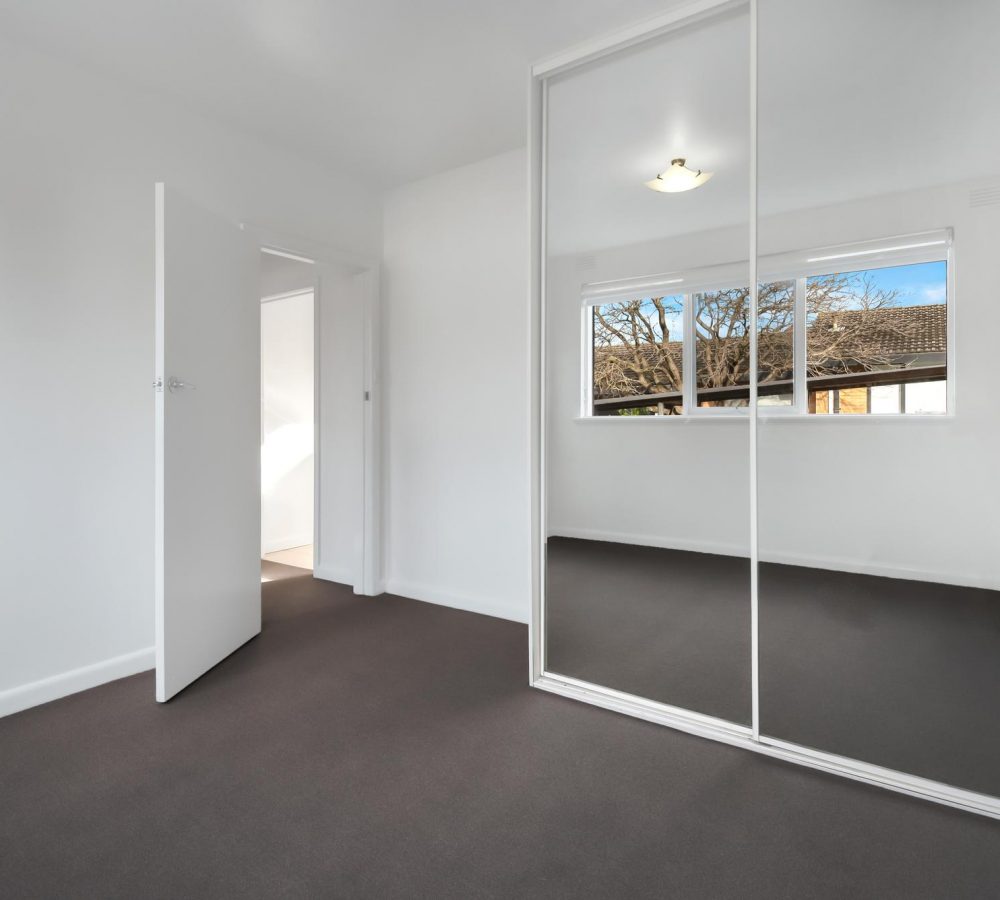 corner-empty-new-room-with-white-walls-wardrobe-with-mirror-sliding-doors